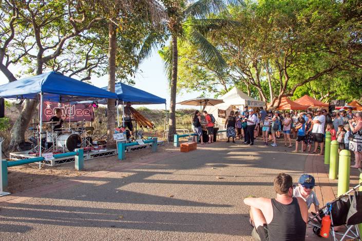 People at Darwin market sitting and standing facing gazebos with bands playing